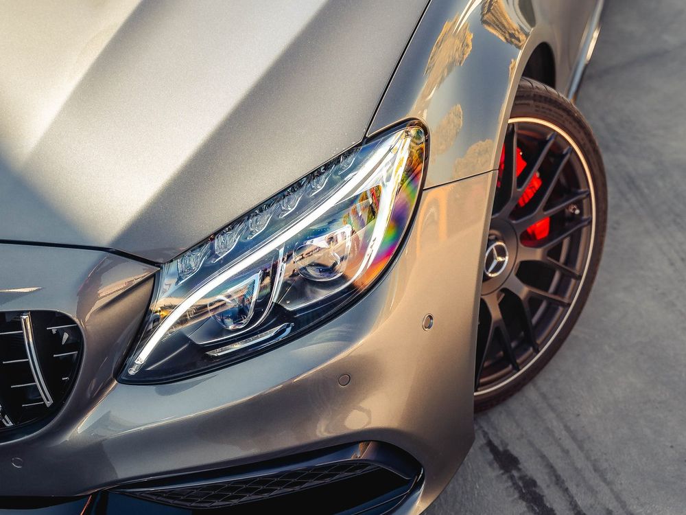 Close-up of a grey Mercedes-AMG C63 W205 headlight, bonnet and red brake caliper
