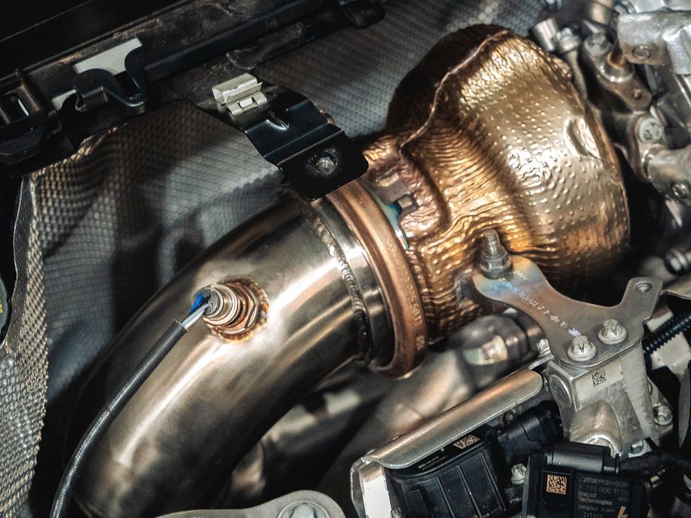 Mercedes-AMG CLA45 S M139 engine bay showing the turbo and a fitted stainless downpipe with heat-coloured welds