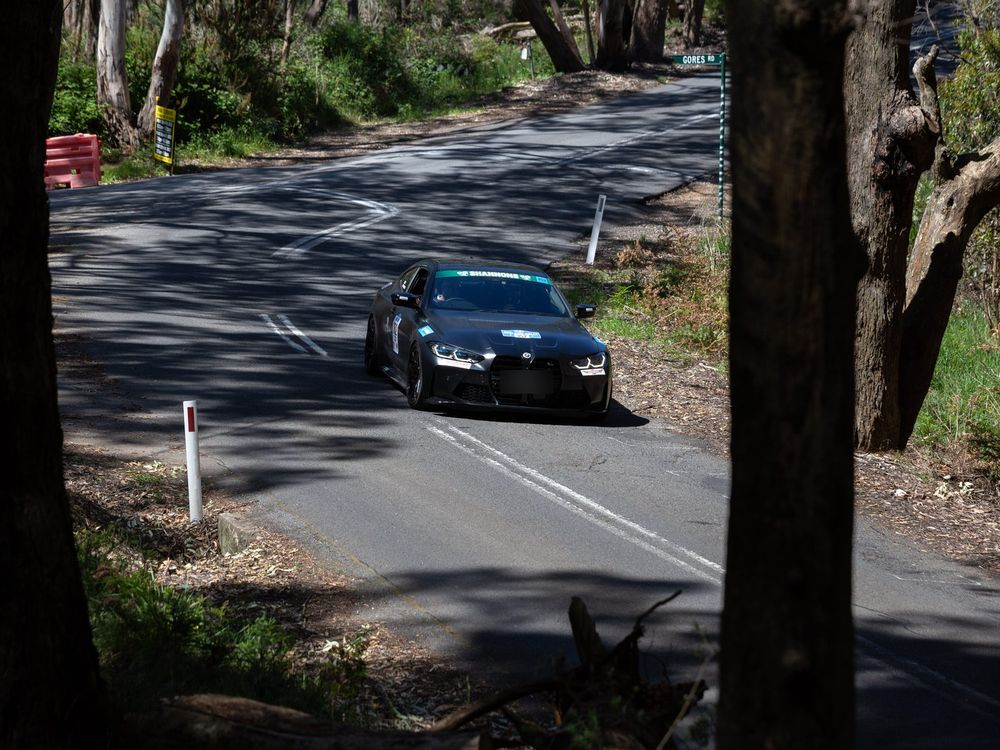 Black BMW M4 (G82) driving up a tree-lined Adelaide Hills road