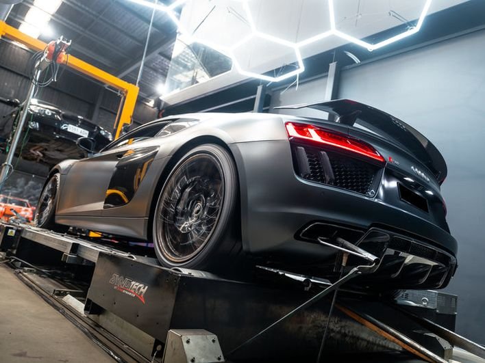 Matte grey Audi R8 on the Dynotech AWD dyno under the hexagonal lights at CADE Technologies