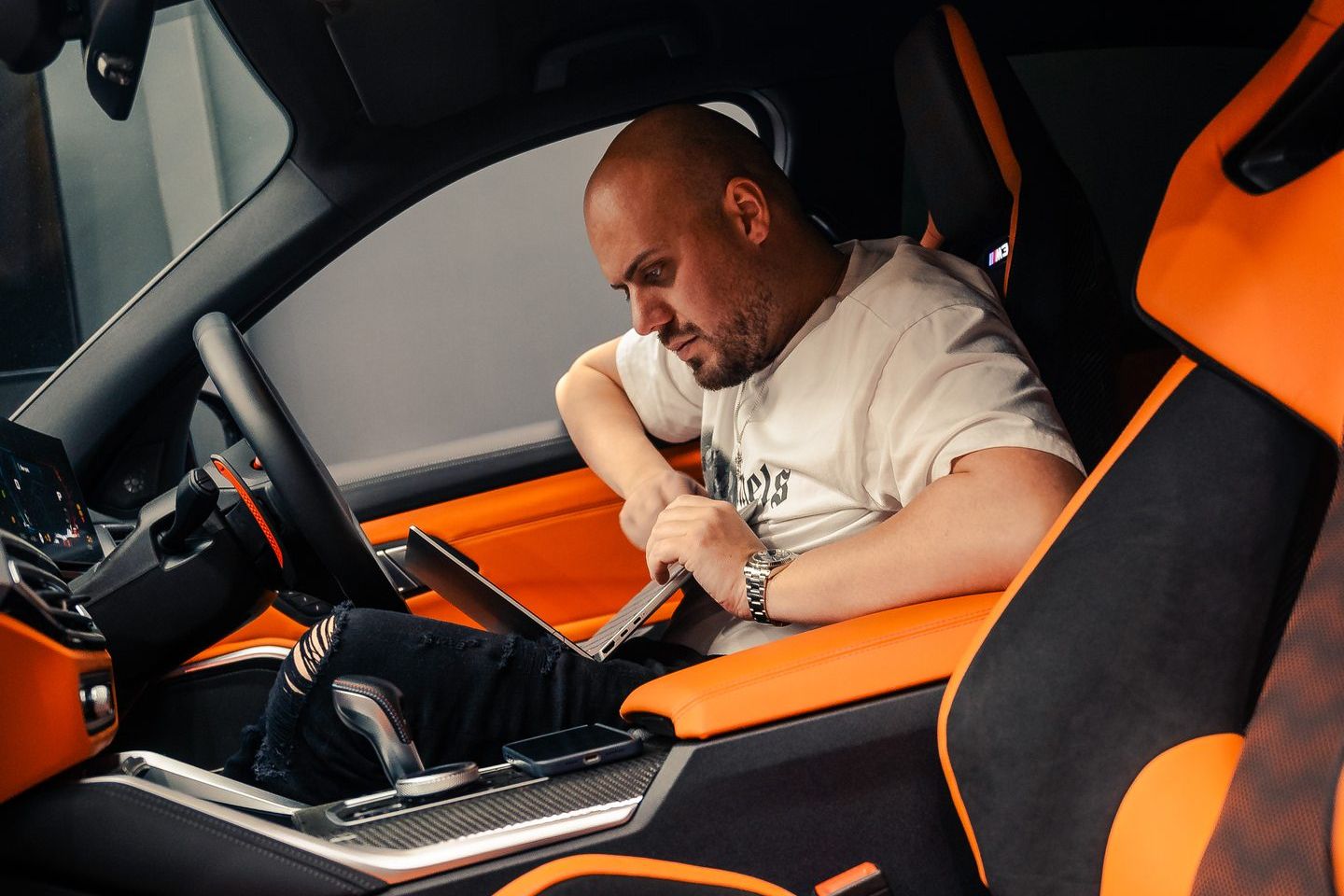 A CADE tuner working on a laptop in the driver&rsquo;s seat of a BMW M3