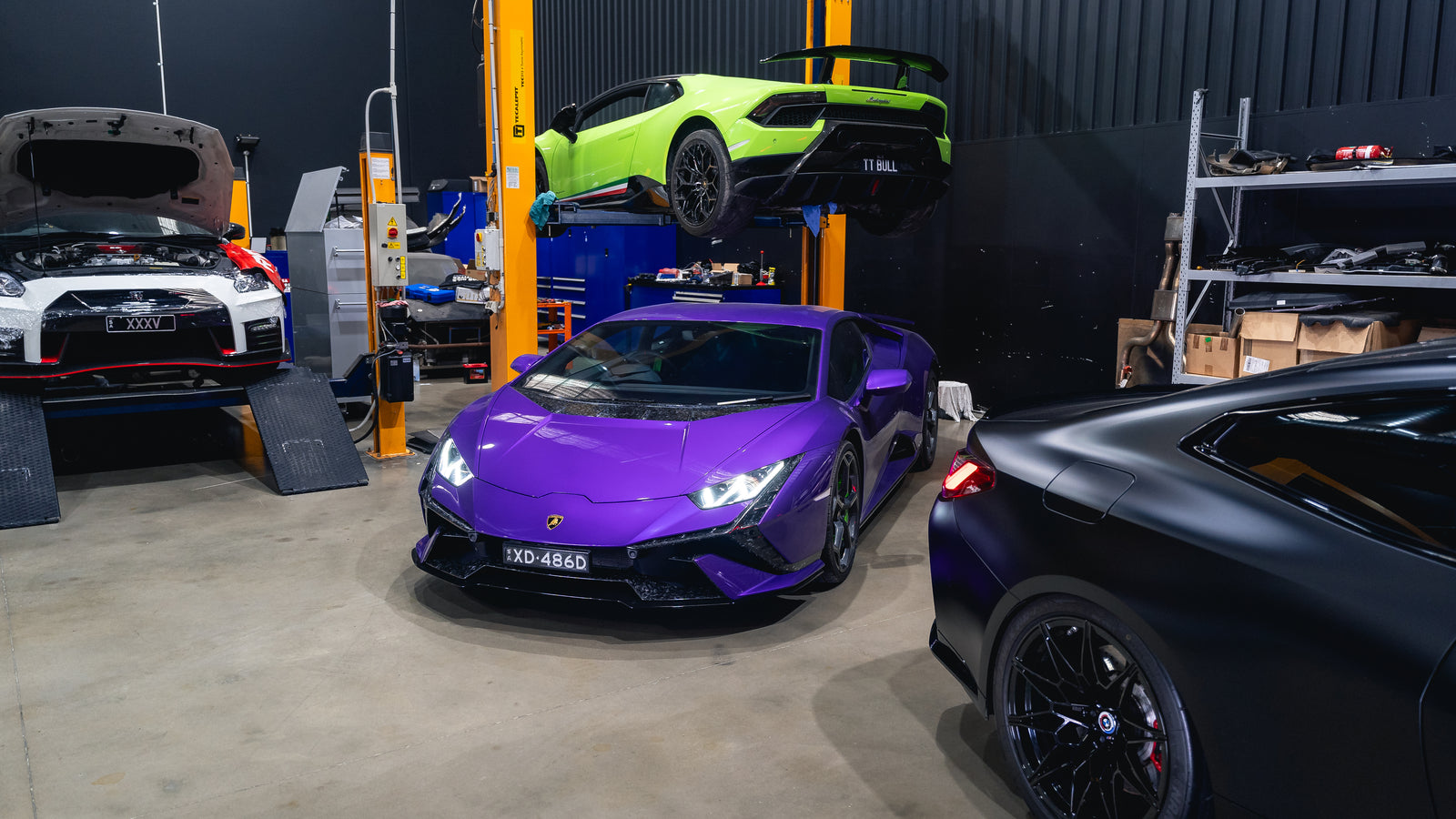 Lamborghini Huracán Tecnica, a Huracán Performante on the hoist, a Nissan GT-R and a matte black BMW in the CADE Technologies workshop