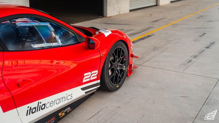Side of a red Ferrari race car with number 22 livery in a pit lane