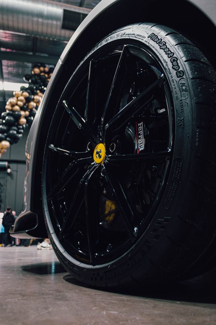 Low-angle close-up of a black Ferrari wheel with a yellow centre cap and Michelin Pilot Sport Cup 2 tyre