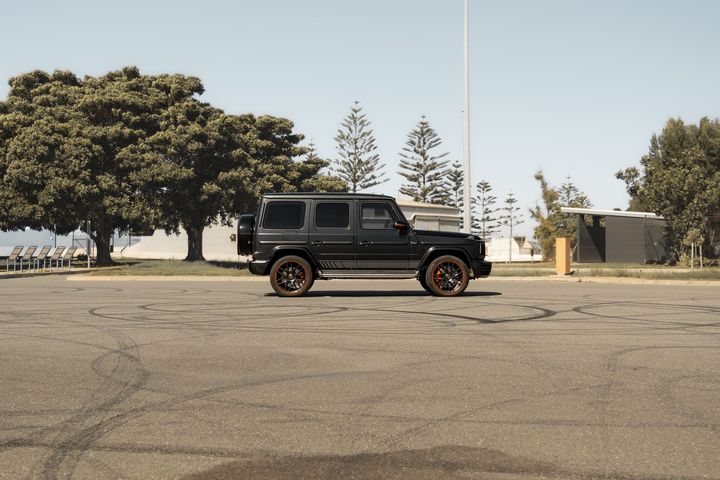 Matte black Mercedes-AMG G63 parked side-on on an open tarmac lot