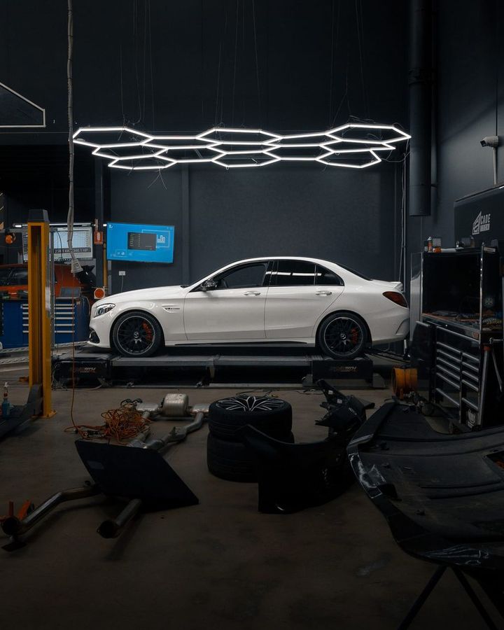 White Mercedes-AMG C63 S sedan under the hex lights in the CADE Technologies workshop
