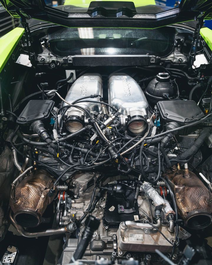 Engine bay of a green Lamborghini with the intake removed during engine work