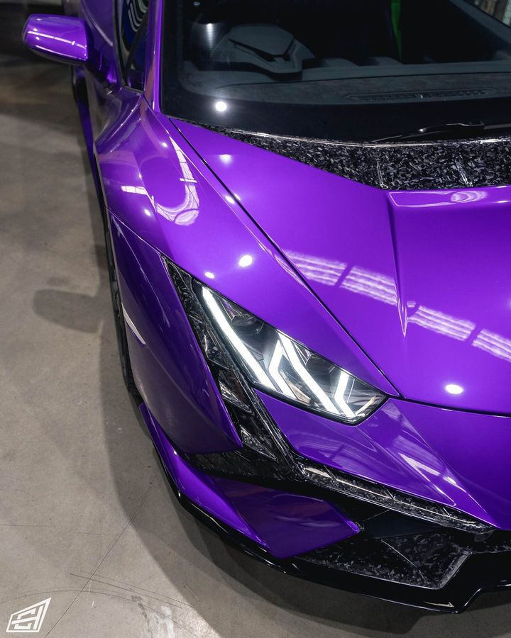 Front corner of a purple Lamborghini Huracán showing the headlight and forged-carbon trim