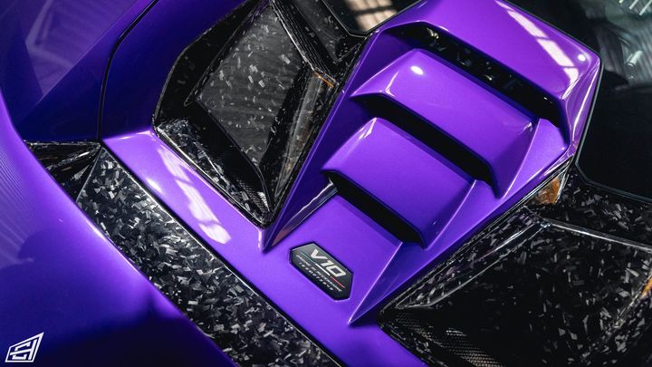 Close-up of a purple Lamborghini engine cover with forged-carbon trim and V10 badge