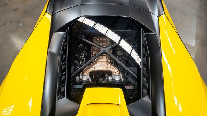 Top-down view into the engine bay of a yellow Lamborghini with a carbon X-brace