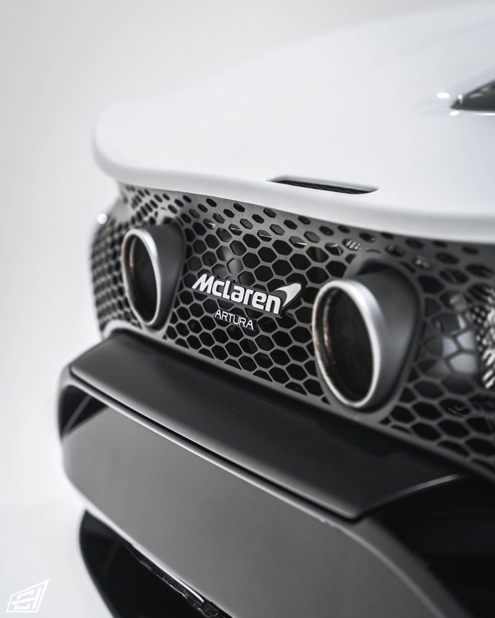 Rear of a white McLaren Artura showing the twin exhaust outlets and Artura badge