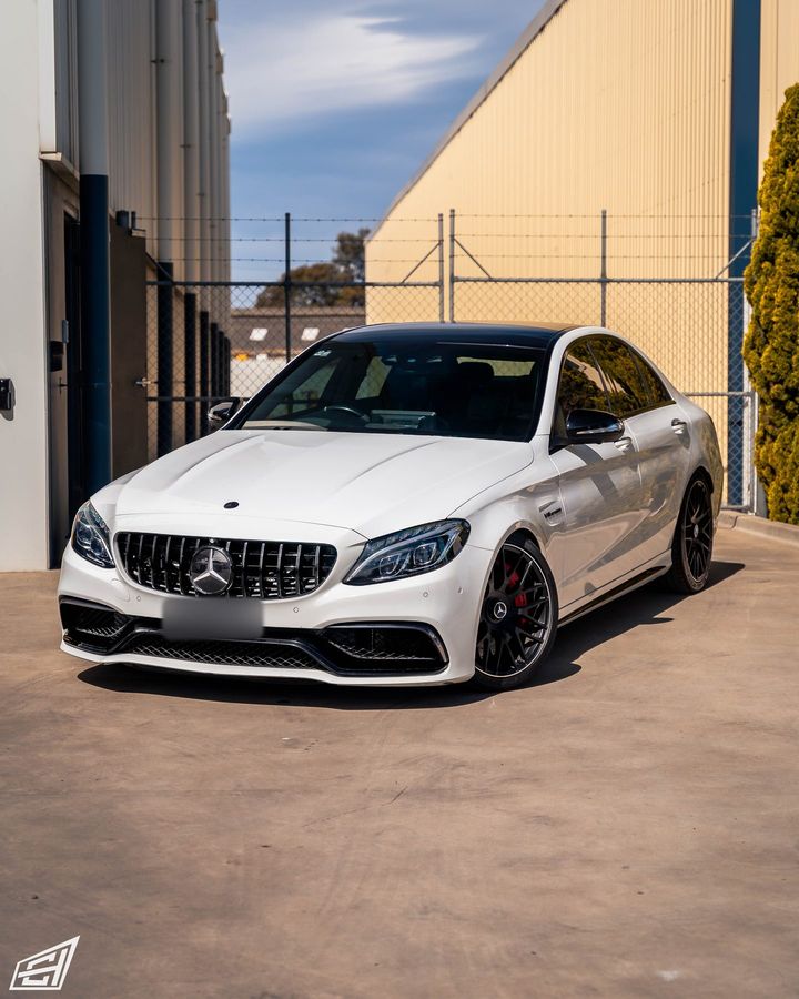 White Mercedes-AMG C 63 S sedan parked outside the workshop, front three-quarter view