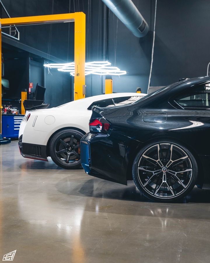 Black BMW M2 (G87) parked beside a white Nissan GT-R in the CADE Technologies workshop
