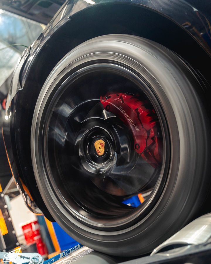 Porsche wheel with crest centre cap and red brake caliper spinning on the dyno