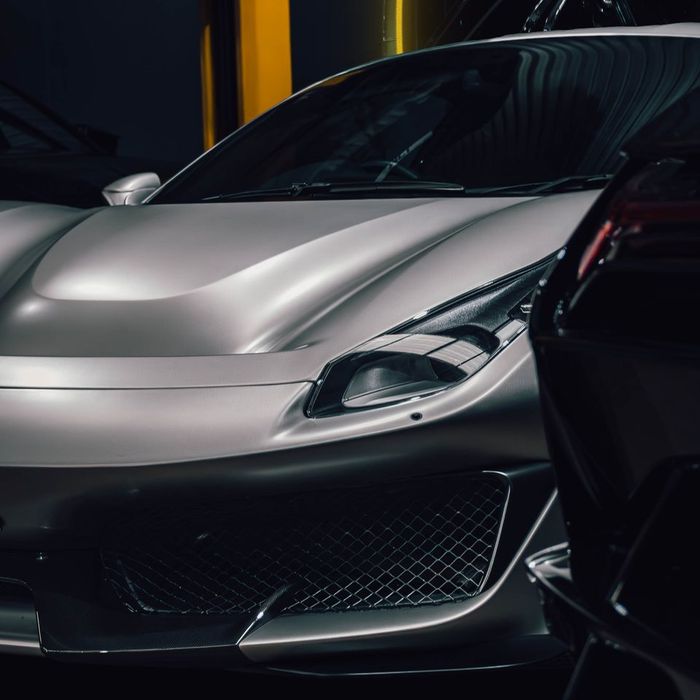 Silver Ferrari 488 Pista nose beside a black supercar in the CADE workshop