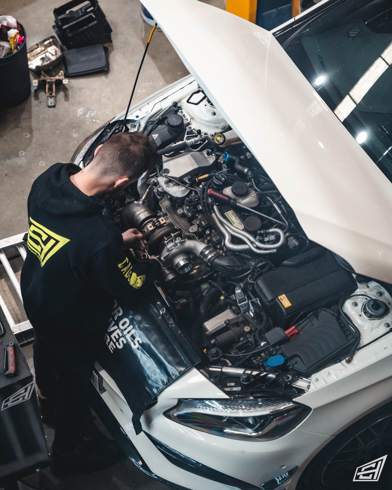 CADE technician working in the engine bay of a white Mercedes-AMG A45