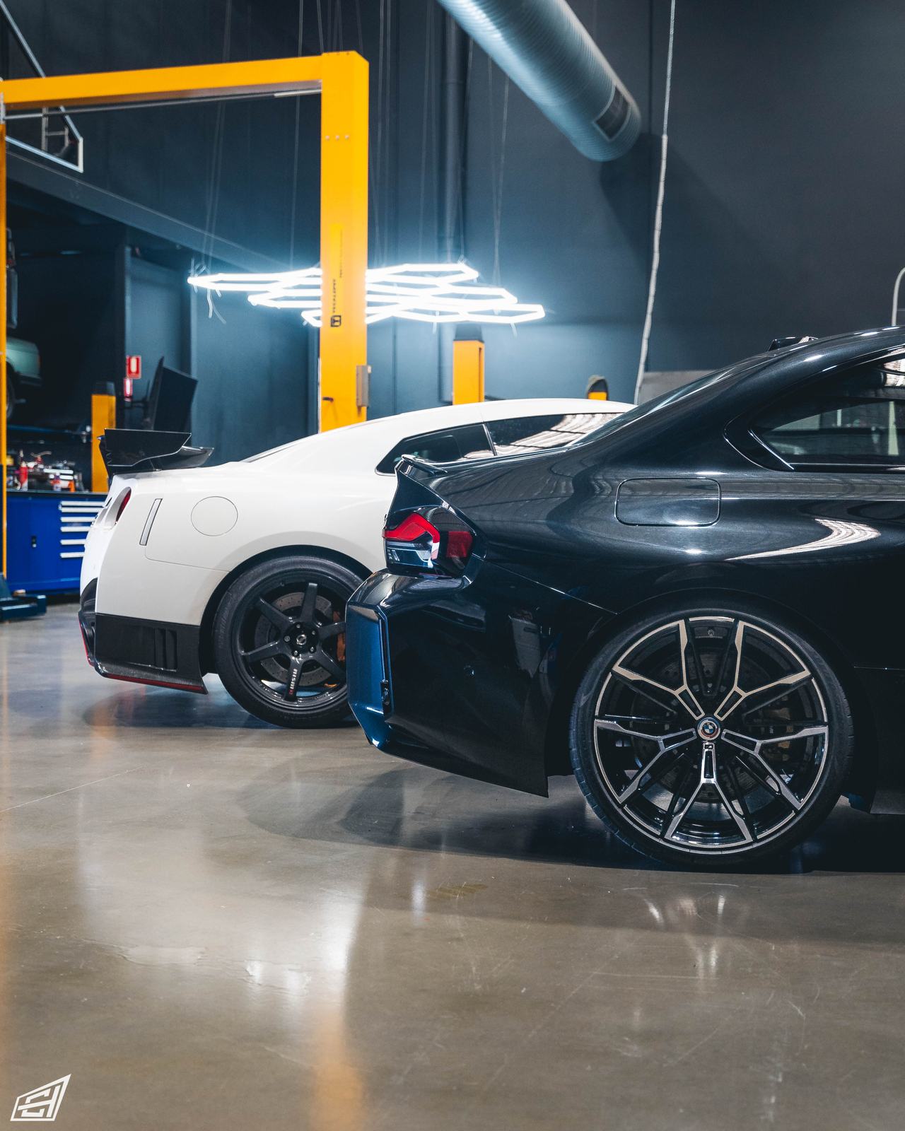 Black BMW M2 (G87) parked beside a white Nissan GT-R in the CADE Technologies workshop