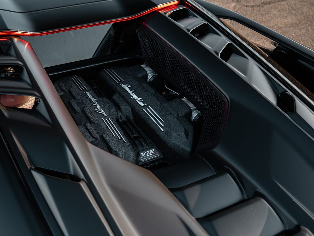 Top-down view of the Lamborghini Revuelto V12 engine bay with carbon covers and orange accents