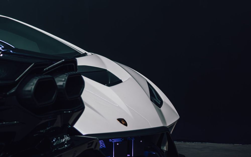 Rear of a white Lamborghini Huracán STO under low workshop lighting