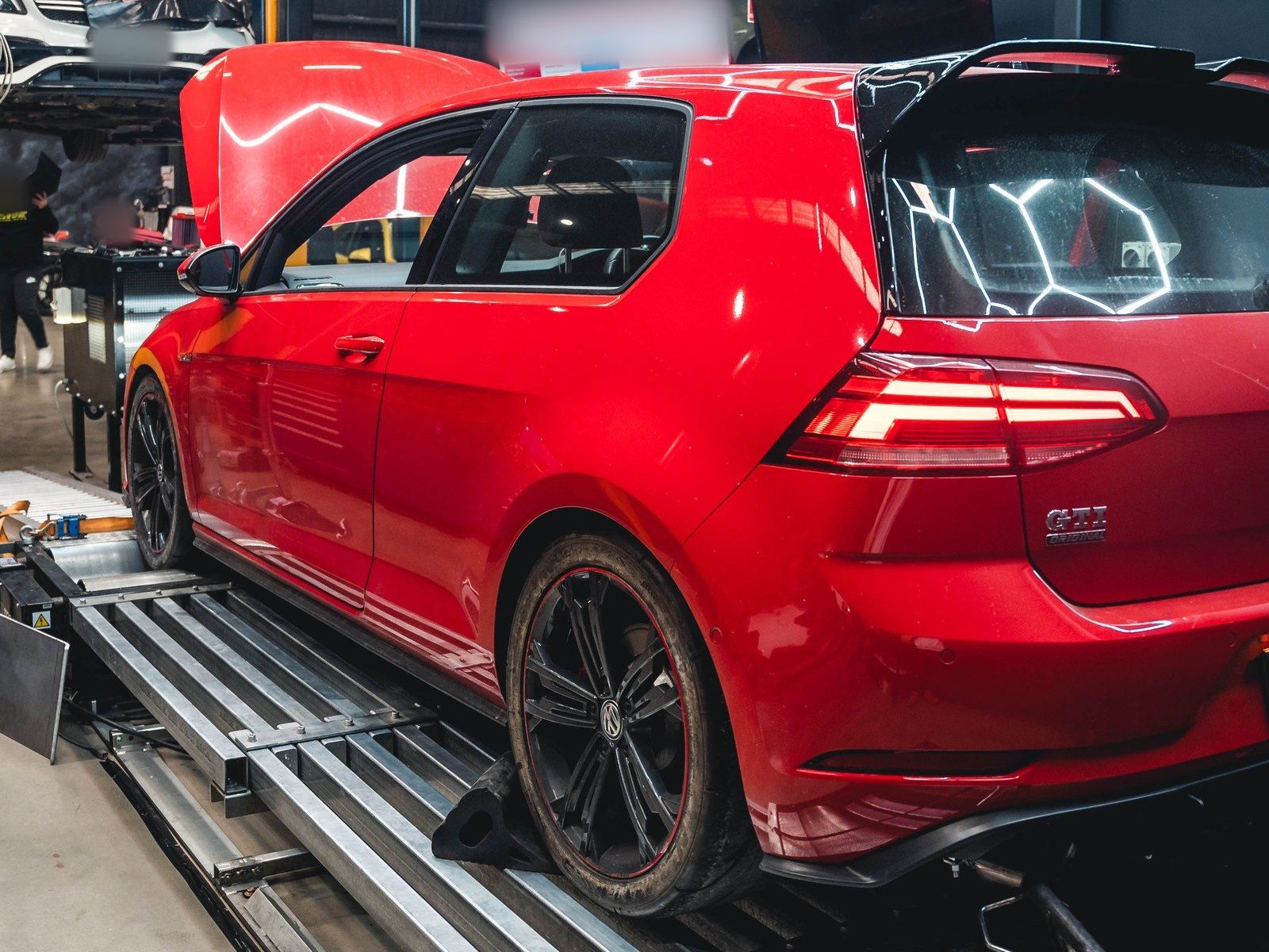 Red Volkswagen Golf GTI (Mk7.5) on the dyno with its bonnet raised, rear three-quarter view