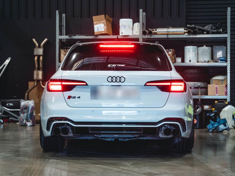 White Audi RS4 Avant, seen from behind with its tail-lights on, in the CADE Technologies workshop