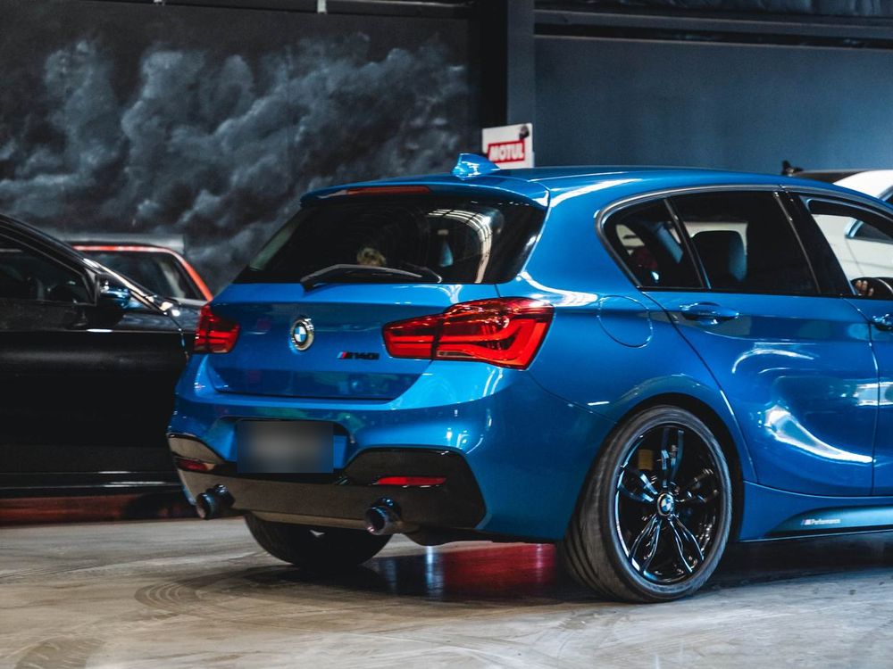 Blue BMW M140i hatch, rear three-quarter view, parked in the CADE Technologies workshop