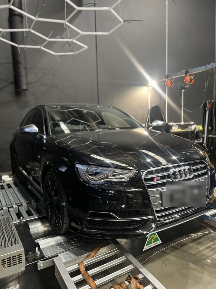 Black Audi S3 sedan (8V) on the dyno beneath hexagonal LED lights, front three-quarter view