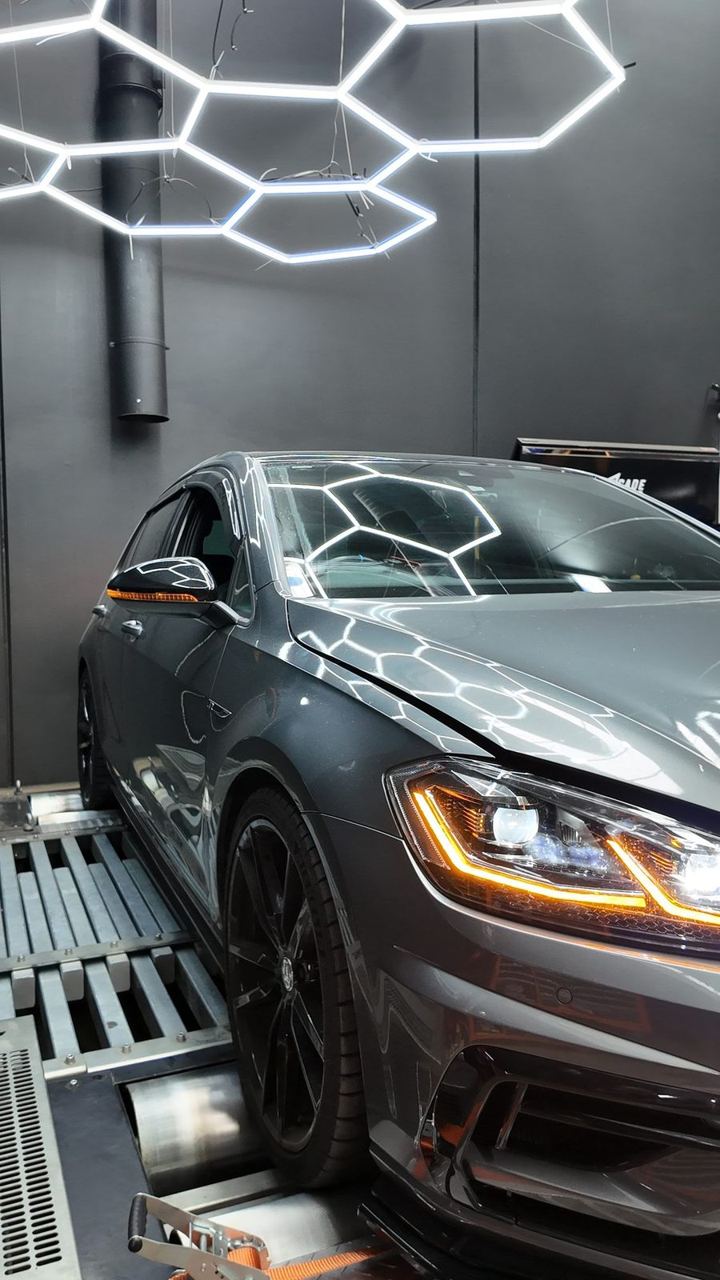 Grey Volkswagen Golf R on the dyno beneath hexagonal LED lights, front three-quarter view